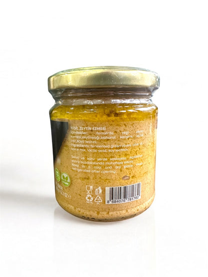 Jar of green olive paste with a gold lid on a white background