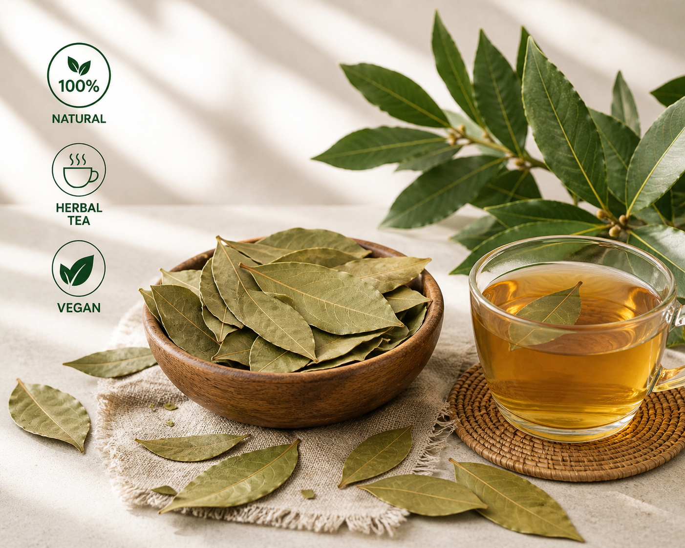 Bowl of dried leaves next to a cup of bay leaf tea with green leaves, on a light background.